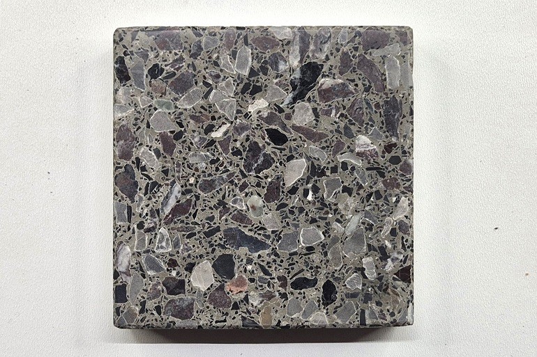 Donkergrijs terrazzo met Sint-Anna, Rosso Levanto en Nero, met een levendige structuur van grijze, zwarte en donkerrode natuursteenfragmenten.