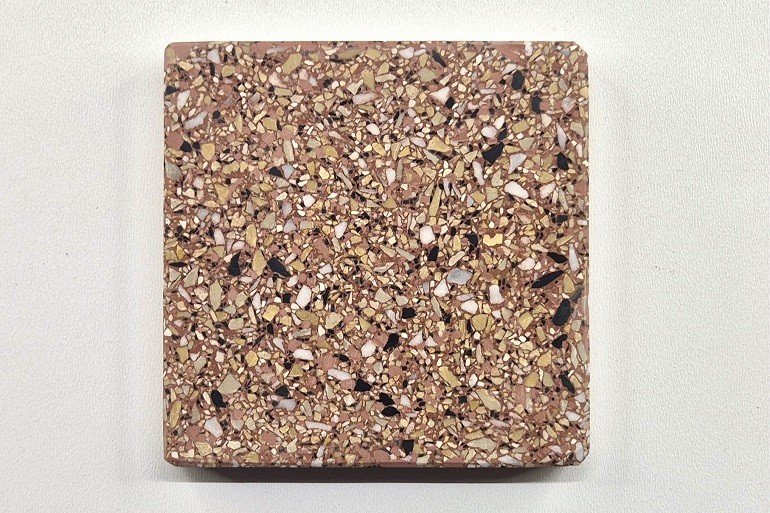 Rood terrazzo met geel Mori, Carrara marmer en Nero, met een levendige structuur van gele, witte en zwarte natuursteenkorrels.
