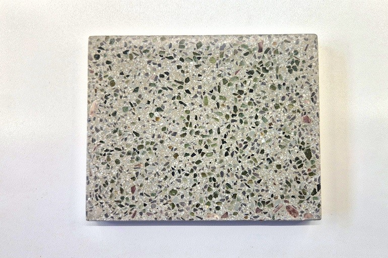 Terrazzo met kleine gepolijste natuurlijke peridot kristallen in een grijze terrazzo basis.