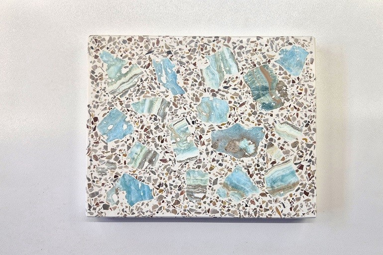 Handgemaakt terrazzo met natuurlijke brokken blauwe aragoniet in een lichte minerale basis.